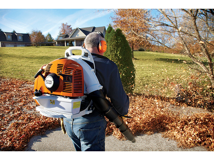 A Stihl backpack blower being used to clear leaves by an operative